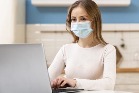 woman-wearing-surgical-face-mask-working-from-home_23-2148480486